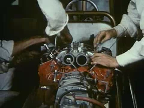 Mechanics securing parts on top of a red engine.