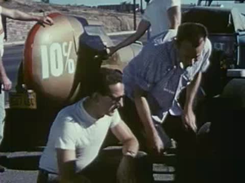 Men adjust equipment and tyres near a race car with 10% marking.