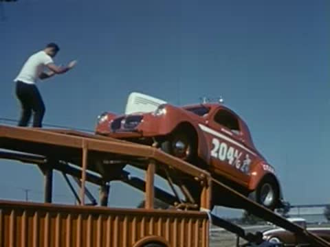 A man walks atop the upper deck of a car carrier transport truck.