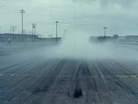 A drag racer accelerates down a track, creating large amounts of smoke.