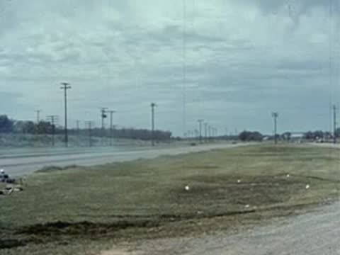 Two cars race down a drag strip in front of a crowd.