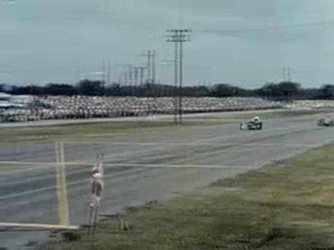 Drag racing cars speed down the track past a crowd of spectators.