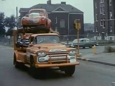 orange car carrier truck driving through city, vintage traffic