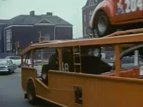 orange car carrier truck turning corner, urban setting