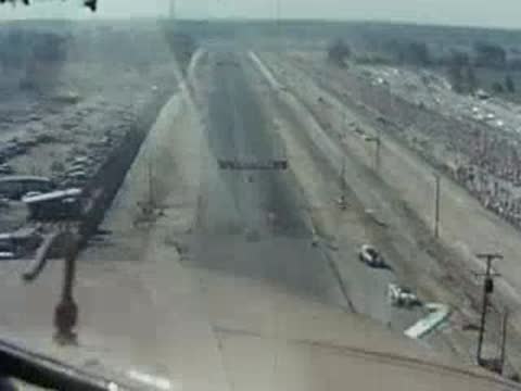 Aerial view of a long drag strip runway with vehicles.