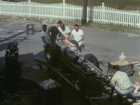 people working on race car outdoors, vintage pit crew