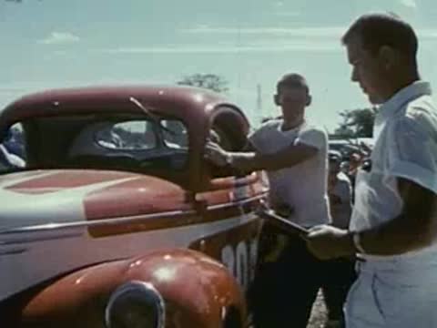 men inspecting vintage race car at event, 1950s show