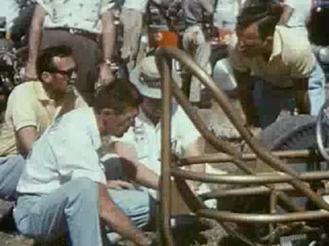 men working on race car chassis, pit area setup