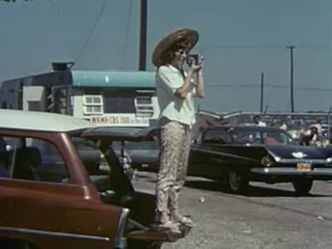 People at a parking lot, a person in foreground is moving quickly.