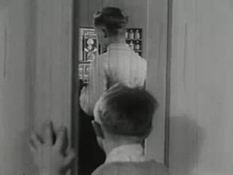 Young boy watching older boy use chemistry set through doorway.