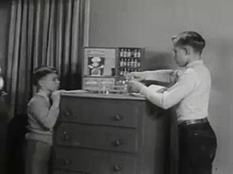 Boy doing chemistry experiments at dresser with family watching.