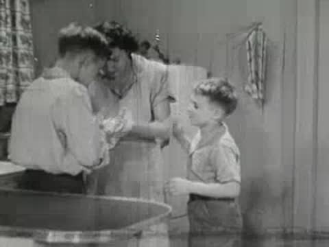 Woman and boy talking in kitchen with table and refrigerator