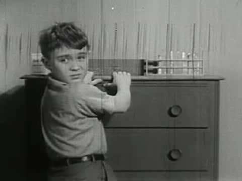 Boy taking chemistry set box off dresser in bedroom