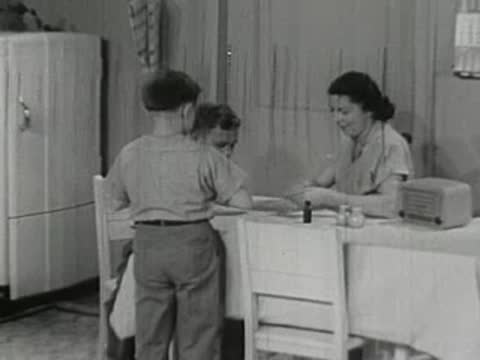 Boy running to woman and another boy at kitchen table
