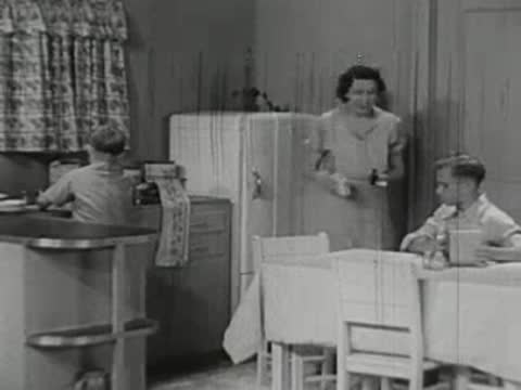 Mother cleaning up a kitchen table as a child sits nearby.