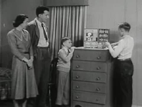 Family watching older boy perform chemistry set experiments.