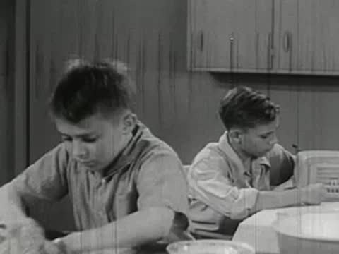 A young child washing dishes in a kitchen sink, washing up.