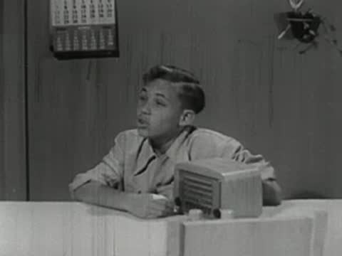 A young boy sitting at a table with a small radio.