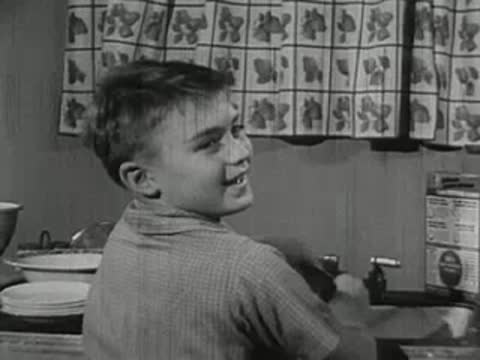 A young boy turning around at a table, looking back.