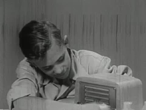 A young boy resting his head near a small table radio.