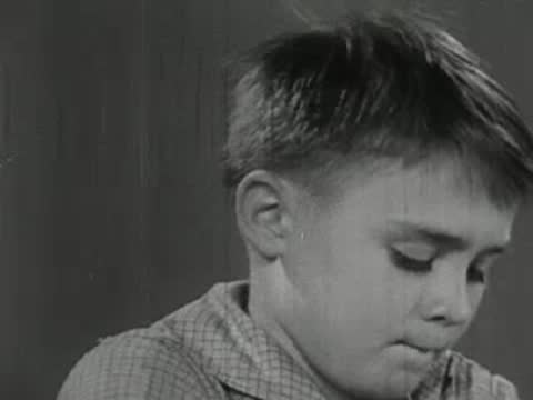 Close-up of a young boy looking thoughtfully and chewing his lip.