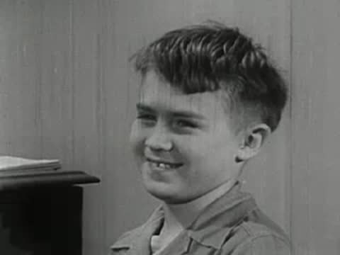 Close-up of a young boy smiling and looking off to the side.