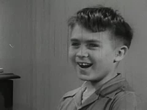 Close-up of an older boy talking while a younger boy smiles nearby.