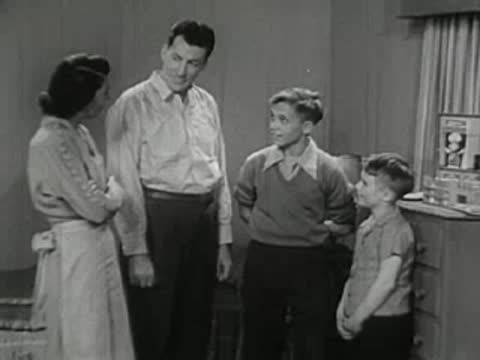 A family standing together in a room, watching a chemistry set.