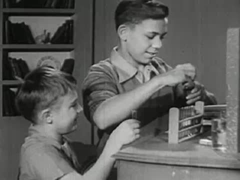 Two boys working together with chemistry equipment at a counter.