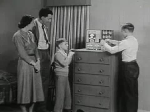 Family observing boy playing with chemistry set.