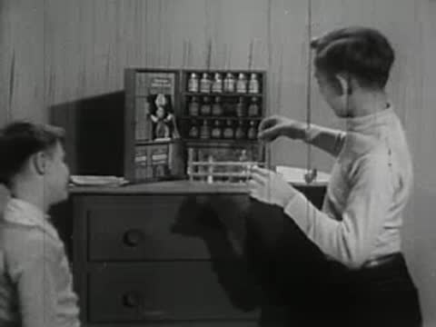 Older boy doing chemistry experiments while younger boy watches.