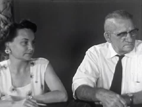 Elderly man and woman sitting together at a meeting or conference, 1950s.
