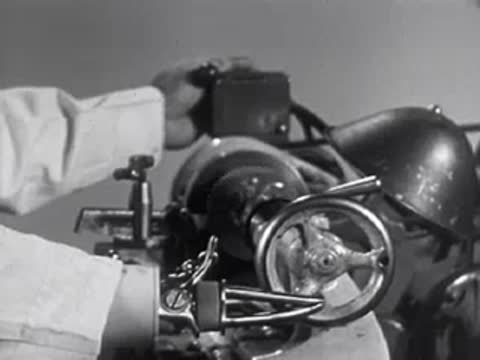 Man operating industrial lathe machine in factory, dissolve transition, 1950s.