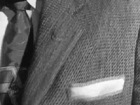 A close-up of a person's hands wearing a ring, adjusting a textured fabric jacket.