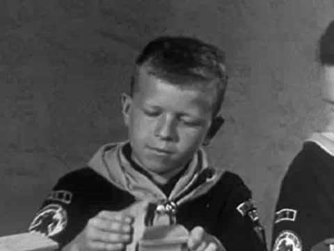 Cub scout smiling while working on a project, 1950s youth organization.