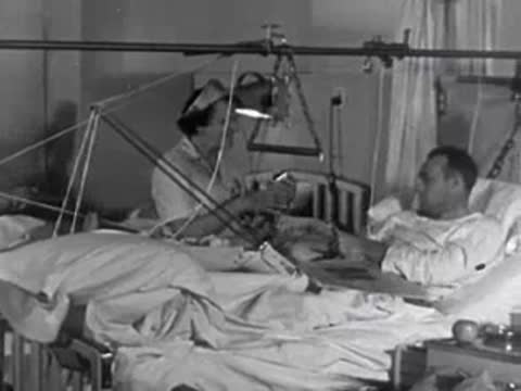 A nurse tending to a patient in a hospital bed with overhead traction equipment.