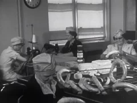 A group of women assembling pretzels or food items on a long table.
