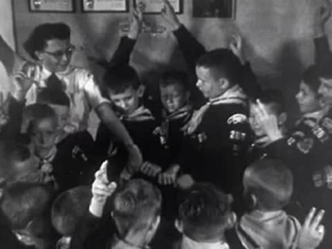 Group of cub scouts taking an oath or pledging, 1950s.