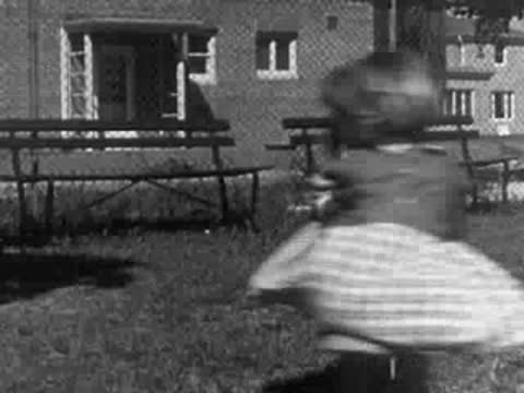 Children playing outdoors on a playground merry-go-round and see-saw.
