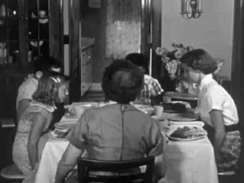People gathered around a dining table in a home with period interior decor.