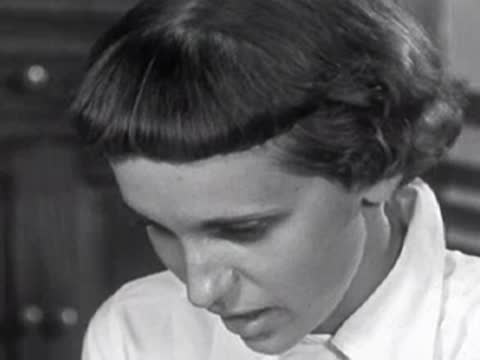 Close-up of a young girl with short hair looking down, possibly reading or eating.
