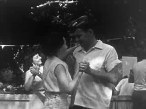 A man and woman dancing together outdoors at a community gathering or picnic.