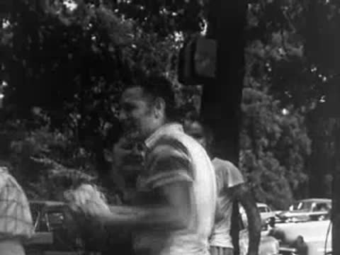 A couple dancing together at an outdoor event with cars parked in the background.