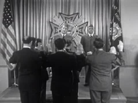 Men raising their hands to take an oath indoors, 1950s.