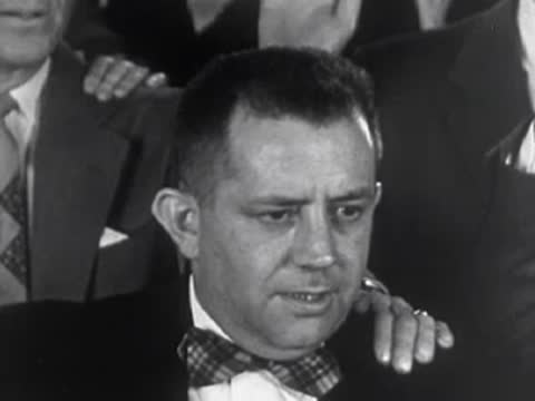 Man in suit with bow tie looking serious, 1950s.