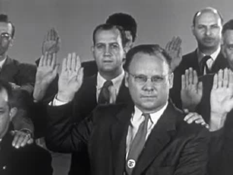 Men in suits taking an oath with raised hands, 1950s.