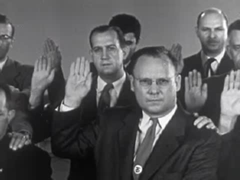 Men in suits taking an oath with raised hands, 1950s.