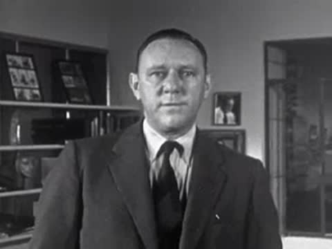 Man in suit looking down and then up in an office, 1950s.