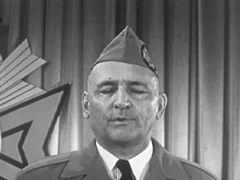 Man in military cap speaking with eyes closed, 1950s.
