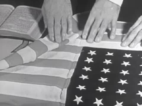 Close-up of hands folding an American flag, 1950s.
